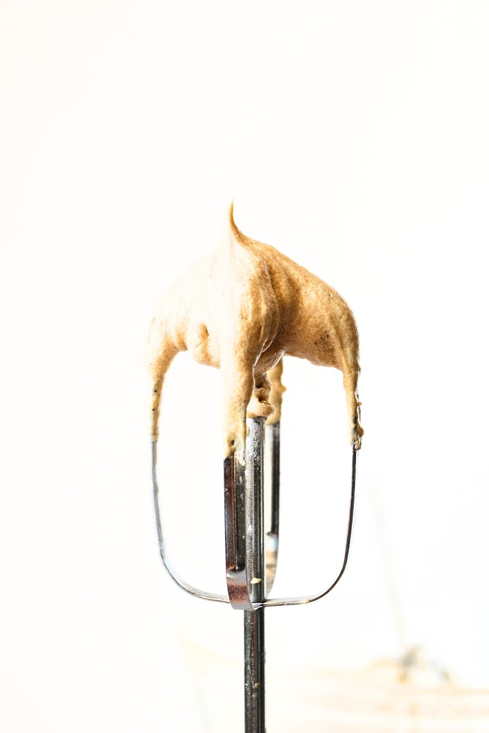 front view of hand held mixer beater with healthy vanilla protein frosting on the tip of the beater