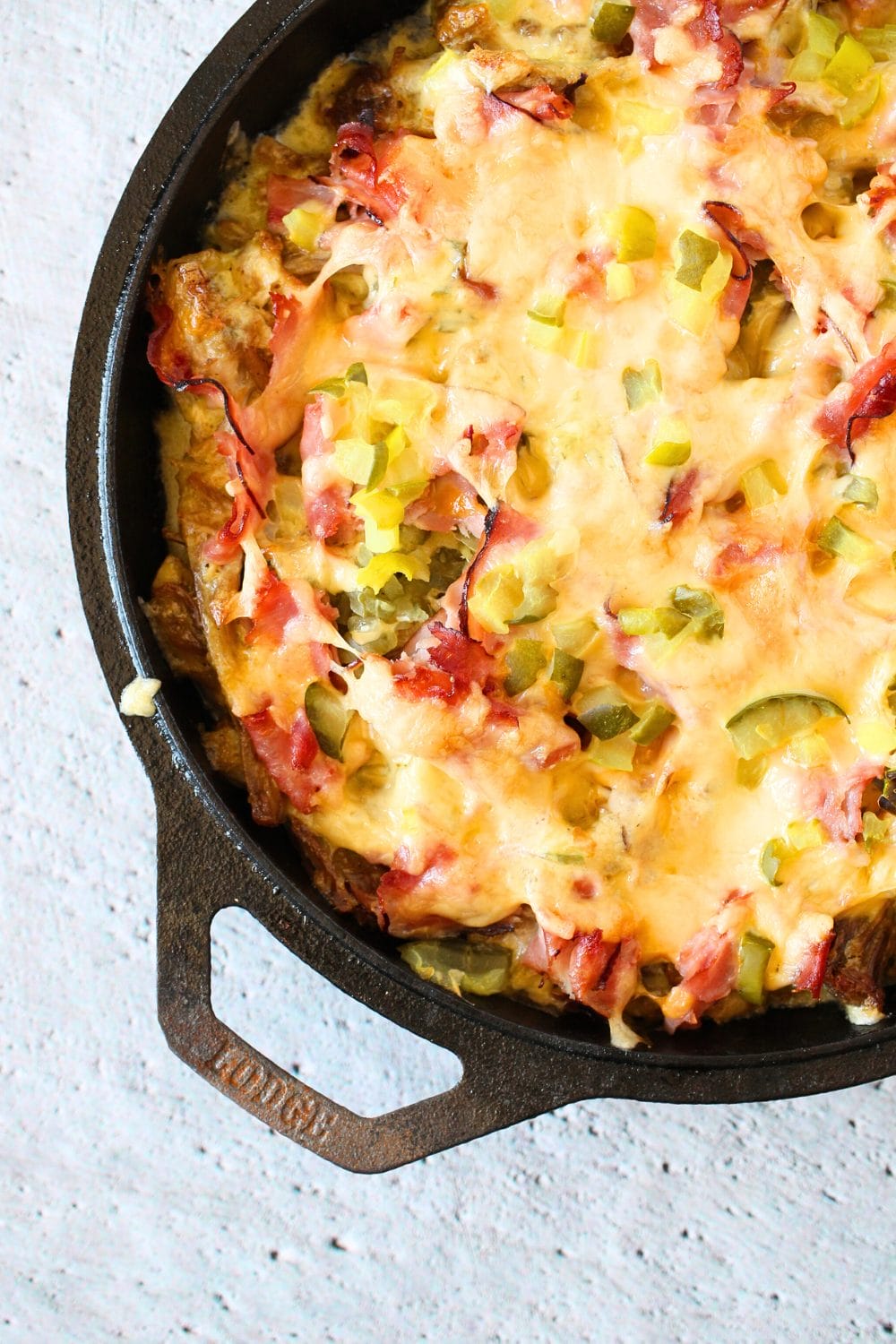 top view of keto cuban casserole with pickles, pork and ham and melted cheese