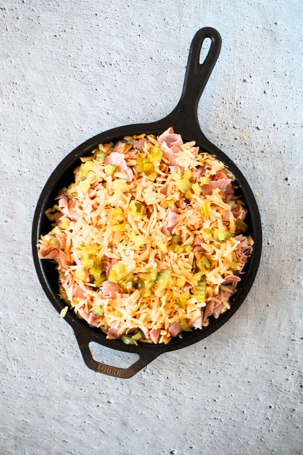 easy keto pork casserole with pork, ham, pickles and cheese before being baked