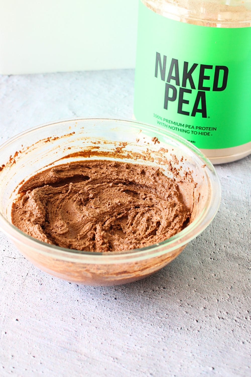 front view of batter for protein keto brownie batter with Naked nutrition pea protein powder jug in the back ground