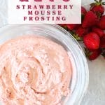 top view of a glass bowl with keto fluffy strawberry mousse and some fresh strawberries scattered around the bowl