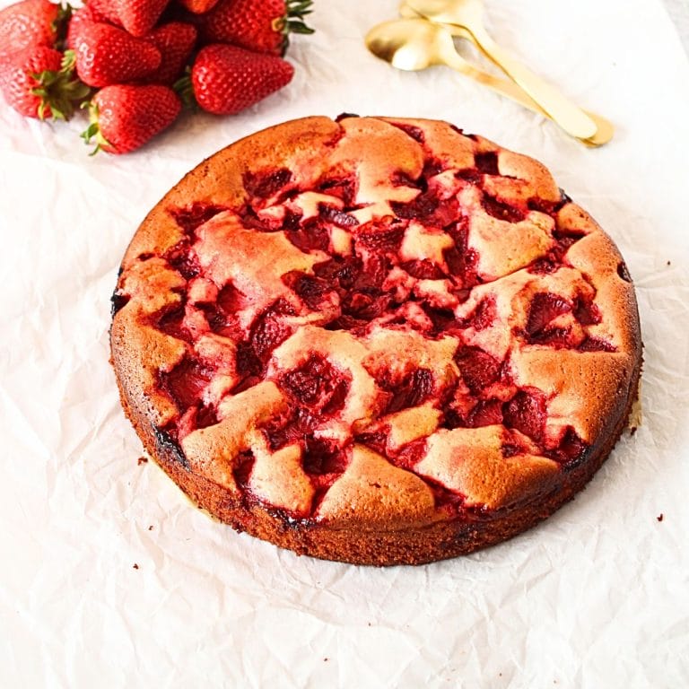 a keto vanilla cake with diced strawberries and an orchid in the background