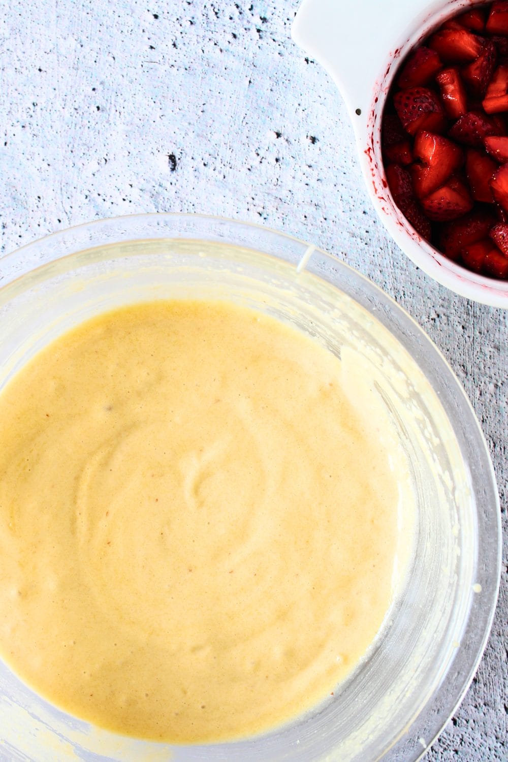 top view of a bowl with low-carb strawberry cake wtih diced strawberries in a bowl to the side