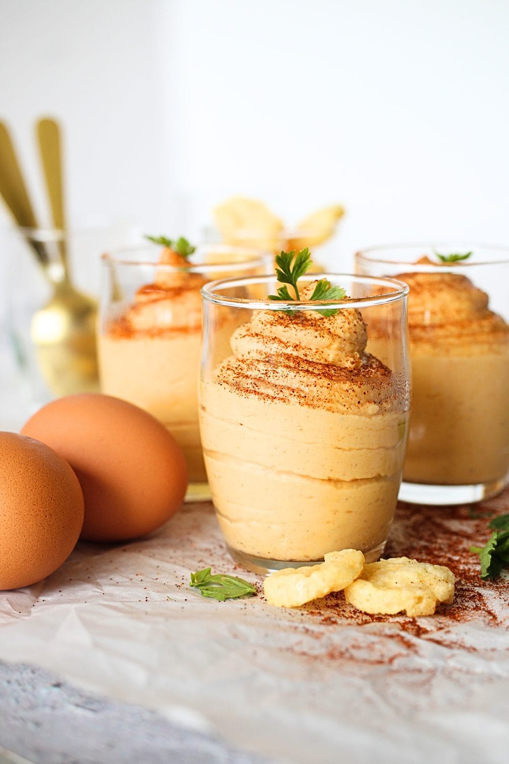 front view of a small glass cup filled with egg fast buffalo dip with parmesan crackers