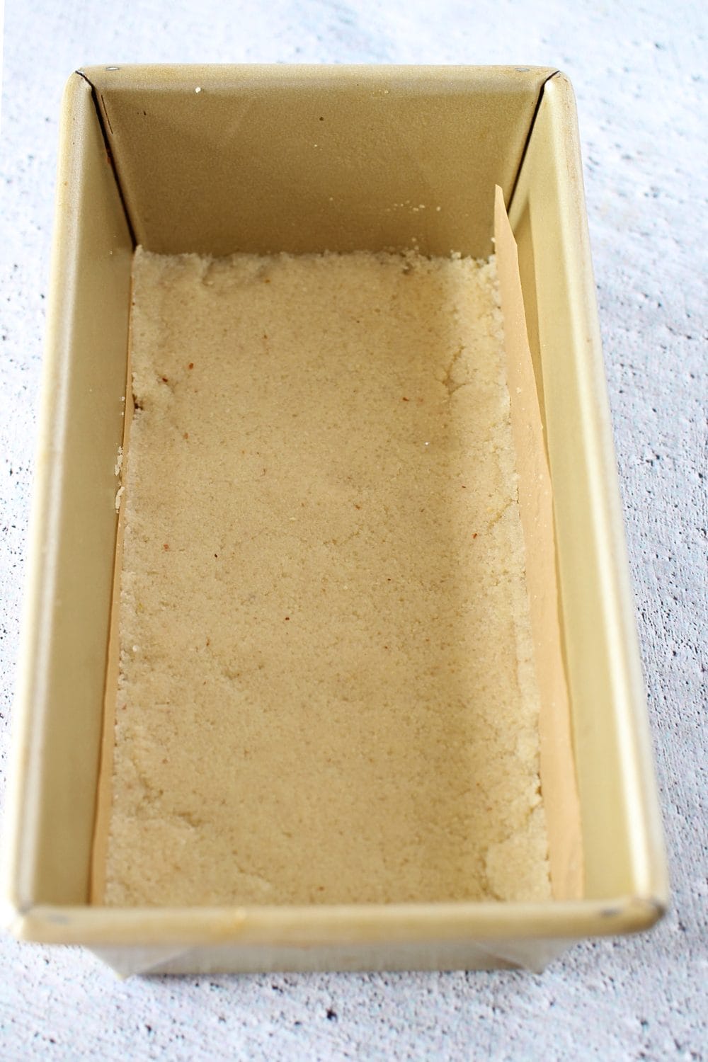 top view of a loaf pan lined with parchment paper and easy keto shortbread cookie batter pressed firmly into pan