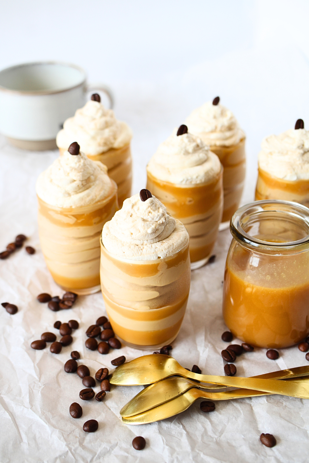 top view of keto caramel mousse cups with sugar-free whipped cream and sugar-free caramel on the side with espresso bean.
