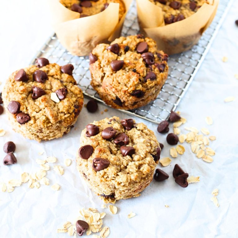 Easy Nut-Free & Gluten-Free Chocolate Chip Banana Oat Muffins that have been baked and are cooling with chocolate chips and oats scattered about