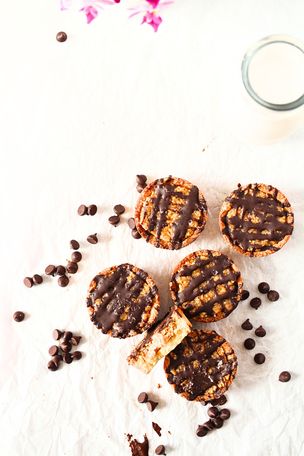 top view of Keto Samoa cookie cups with sugar-free chocolate chips and a glass of almond milk
