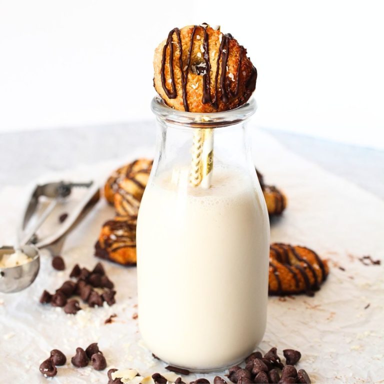 a keto samoa cookie on top of a bottle of almond milk with sugar-free chocolate chips and coconut scattered around