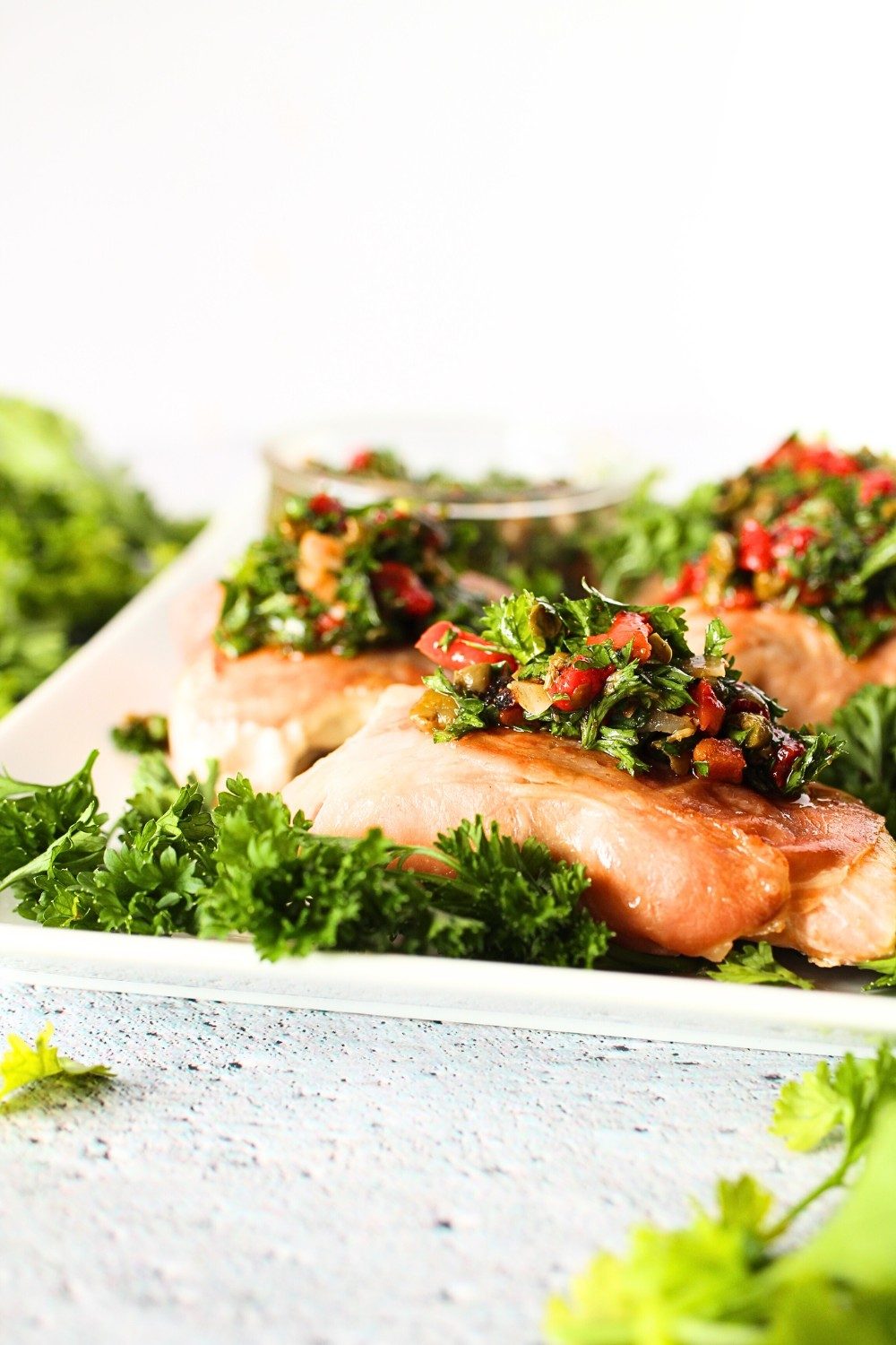 healthy prosciutto-wrapped salmon on a plate with fresh herb dressing on top