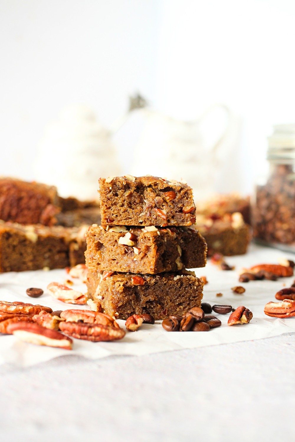 keto coffee nut blondies that are high in fiber stacked on top of each other with nuts scattered about