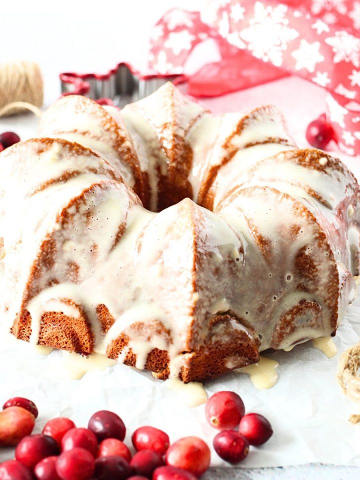front view of keto cranberry vanilla protein bundt cake with fresh cranberries and ribons scattered about