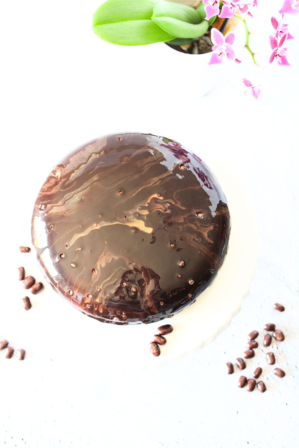 top view of keto chocolate mirror glaze over a cake with chocolate covered coffee beans